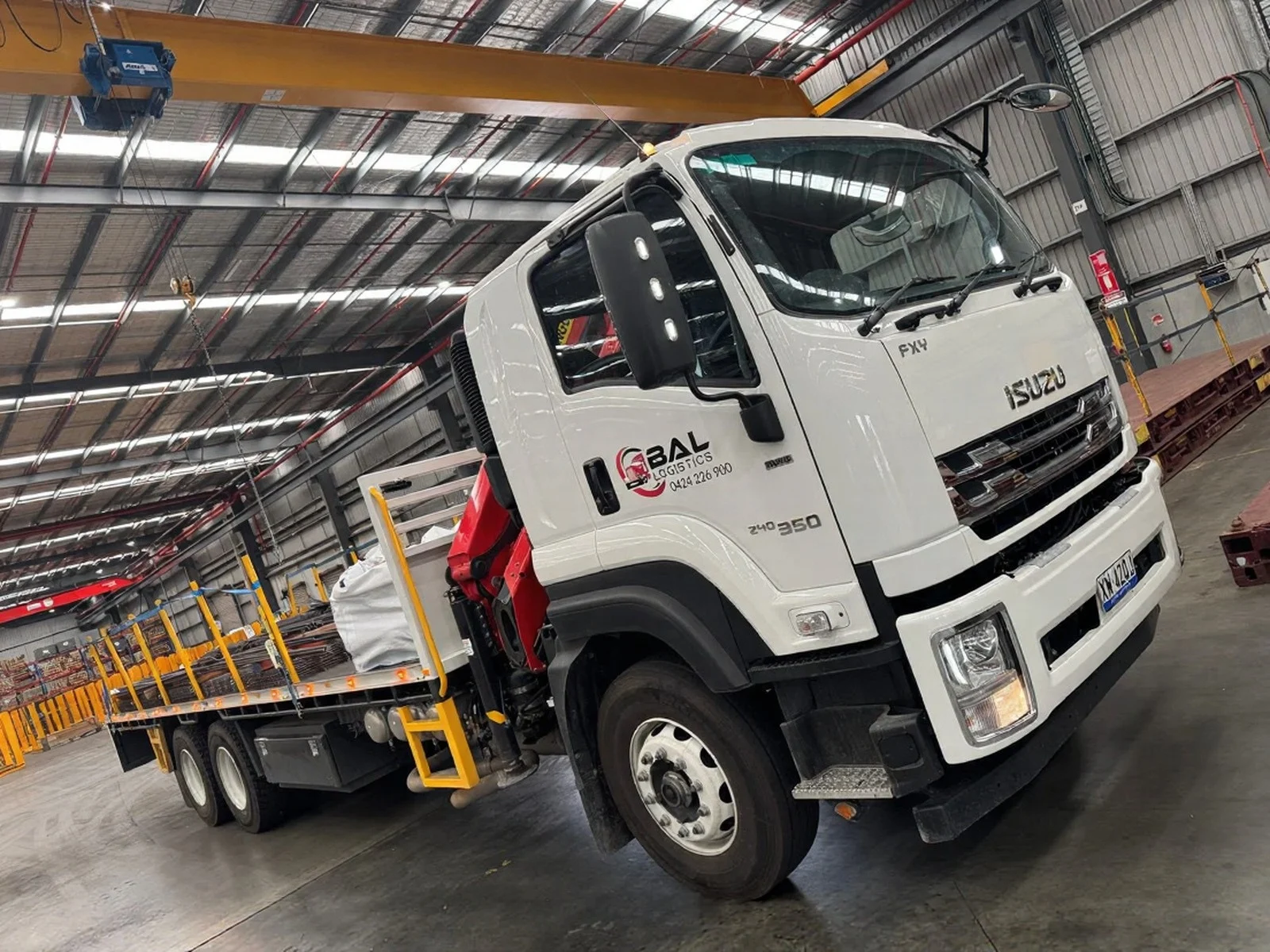 BAL Logistics Isuzu crane truck lifting construction materials beside scaffolding